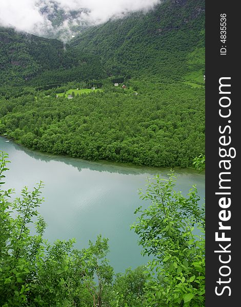 Houses among the nature in Norway, river along the woods, fog