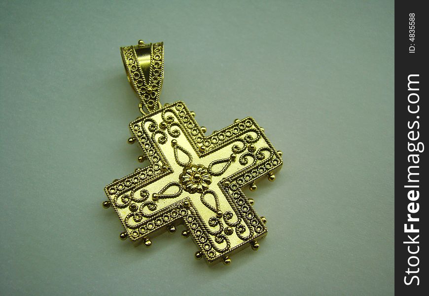 Antique golden cross jewel for necklace lying on paper