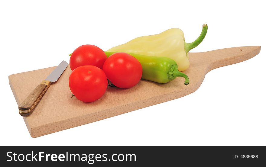 Three tomatoes and two different peppers on a wooden cutting board with knife, isolated on white. Three tomatoes and two different peppers on a wooden cutting board with knife, isolated on white.