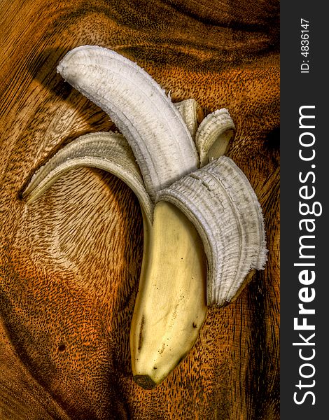 Peeled banana sitting in a wooden bowl.