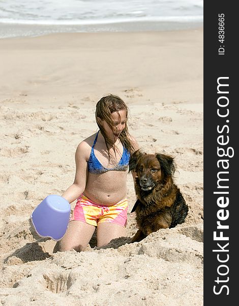 Young girl playing on the beach in the sand with her dog. Young girl playing on the beach in the sand with her dog