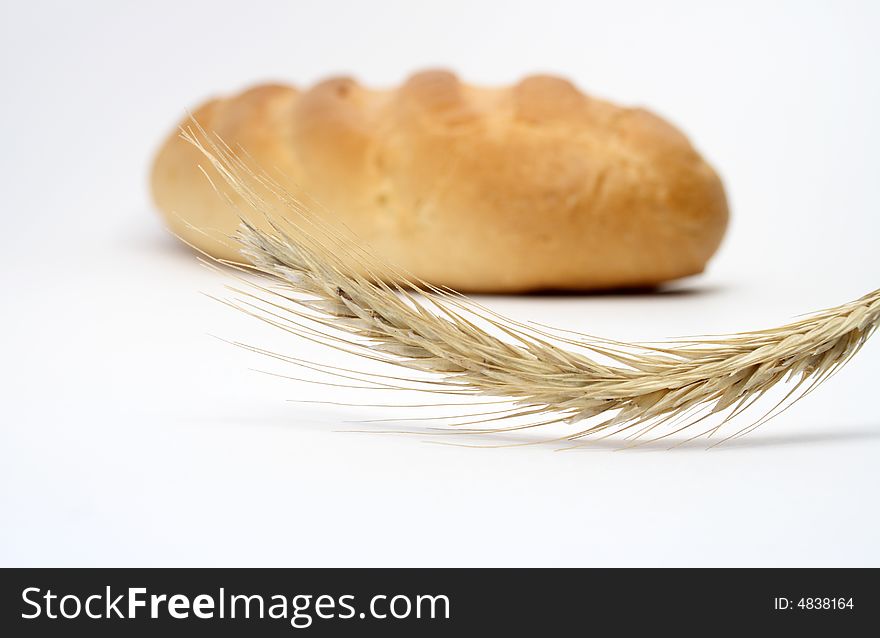 Close-up at wheat ear on background with white bread stick. Close-up at wheat ear on background with white bread stick