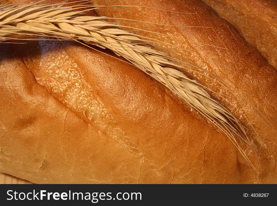 Close-up at wheat ear lying on fresh-baked white bread. Close-up at wheat ear lying on fresh-baked white bread