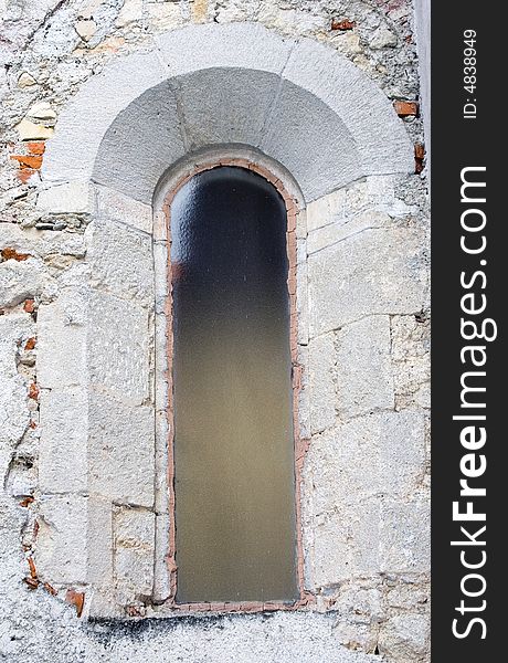 Narrow castle window with glass.