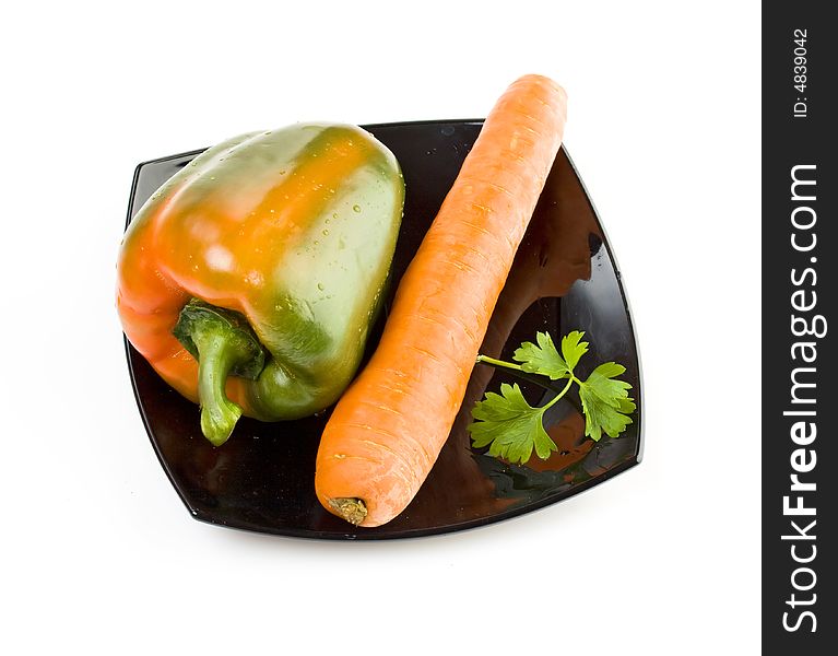 Fresh carrot and green pepper on a black plate, healthy food