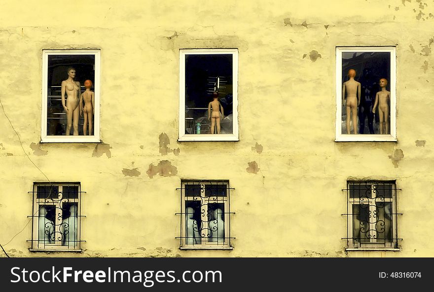 Man woman and child mannequins objects visible from the window of an old building. Man woman and child mannequins objects visible from the window of an old building