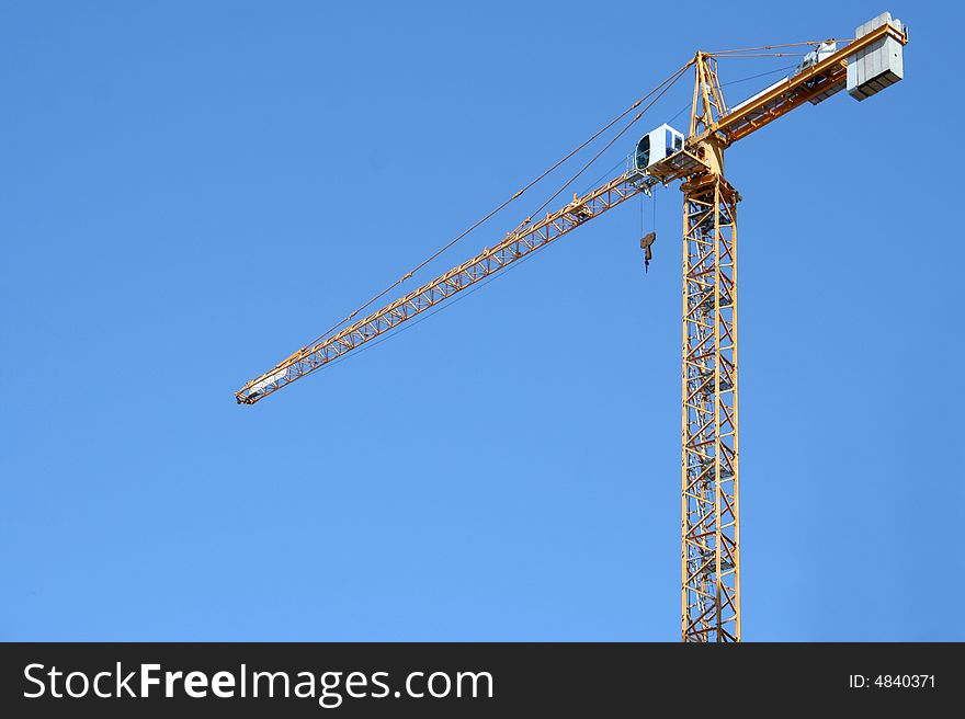 The building crane on a background of the blue sky