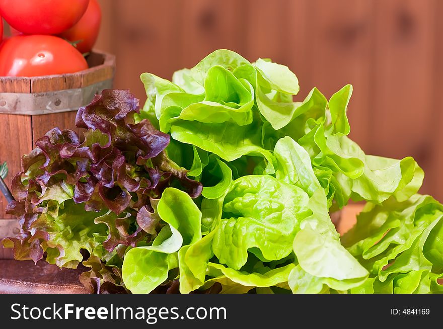 Lettuce and tomatoes in bucket against wooden background. Lettuce and tomatoes in bucket against wooden background