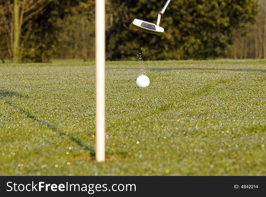 Golf ball on green with flag and putter. Golf ball on green with flag and putter