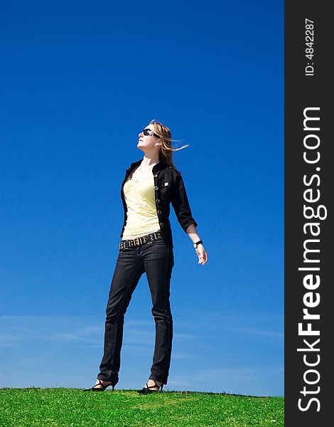 The young attractive girl on a background of the blue sky