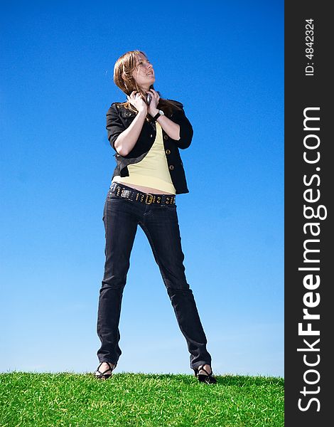 The young attractive girl with headphones on a background of the blue sky