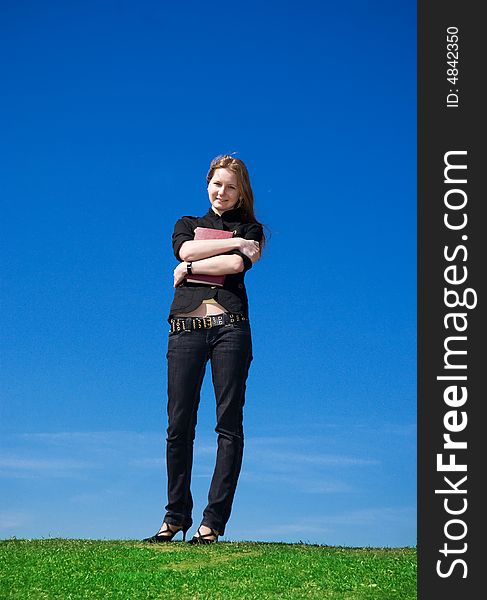 The young attractive student with the book on a background of the blue sky