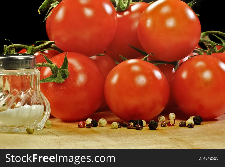 A bunch of tomatoes on wood with salt and pepper. A bunch of tomatoes on wood with salt and pepper