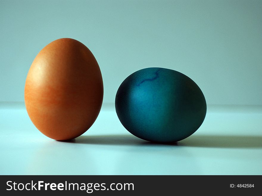 Two colored hard boiled eggs against a blue background. Two colored hard boiled eggs against a blue background.