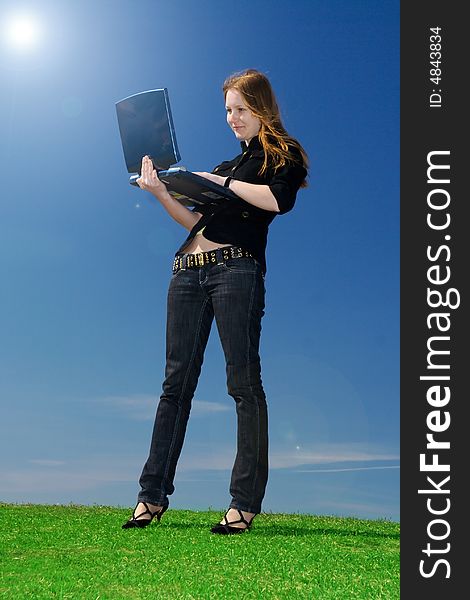 The young attractive girl with the laptop on a background of the blue sky
