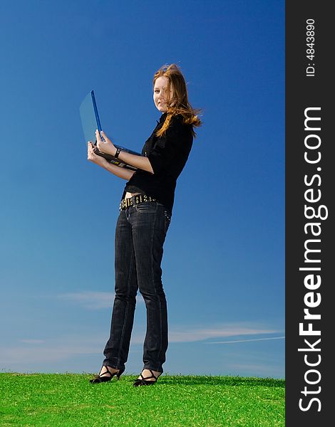The young attractive girl with the laptop on a background of the blue sky