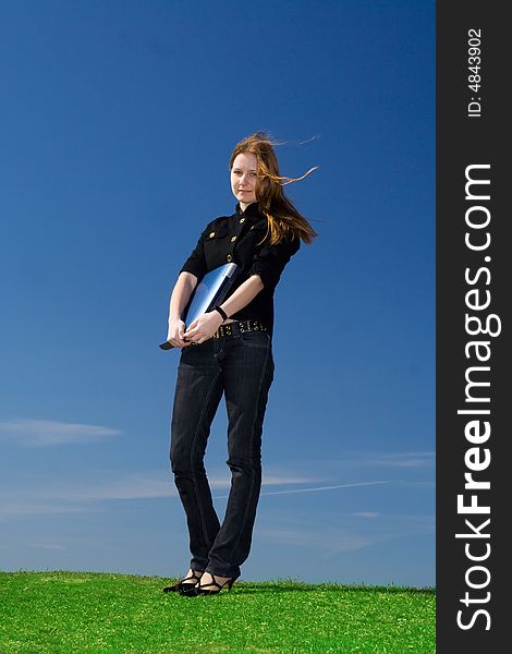 The young attractive girl with the laptop on a background of the blue sky