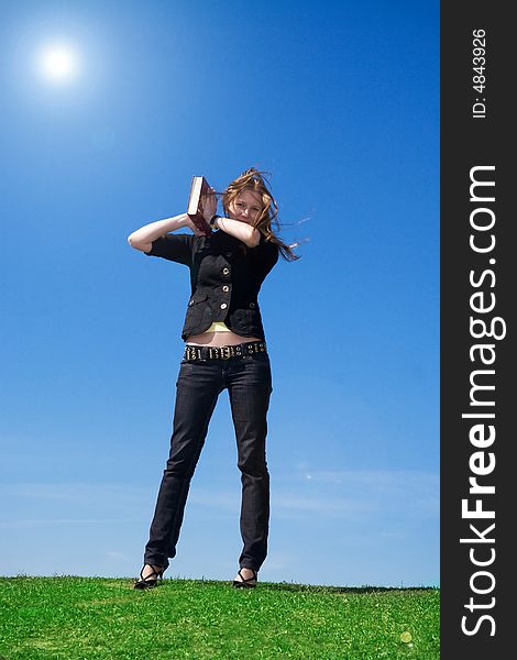 The young attractive student with the book on a background of the blue sky