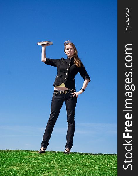 The young attractive student with the book on a background of the blue sky