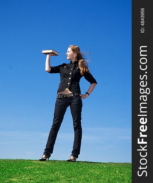 The young attractive student with the book on a background of the blue sky