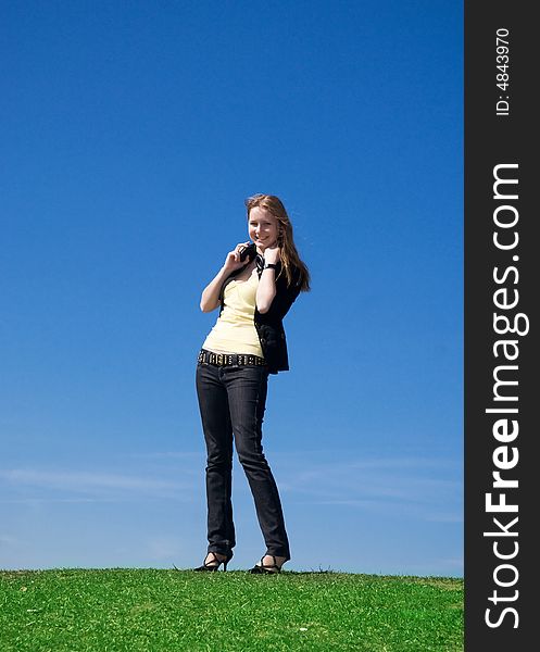 The young attractive girl with headphones on a background of the blue sky