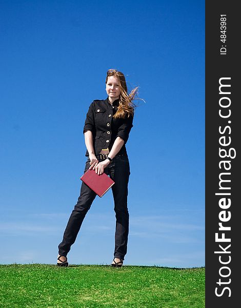 The young attractive student with the book on a background of the blue sky