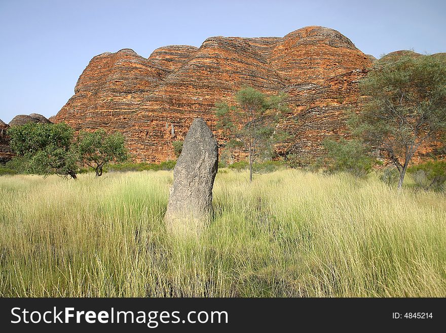 Australian landscape with geological feature of a huge stone peeking from grass and rolling hill in background. Bungle Bungle national park, Western Australia. Australia. Australian landscape with geological feature of a huge stone peeking from grass and rolling hill in background. Bungle Bungle national park, Western Australia. Australia