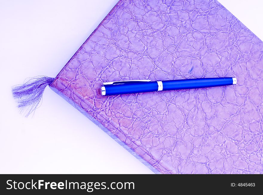 A high key photo of a book or notebook with a pen as the bookmark. A high key photo of a book or notebook with a pen as the bookmark.