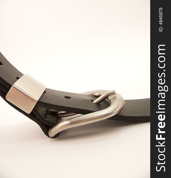 Image of a curved black belt with metal buckle. Vertical orientation. Image of a curved black belt with metal buckle. Vertical orientation.