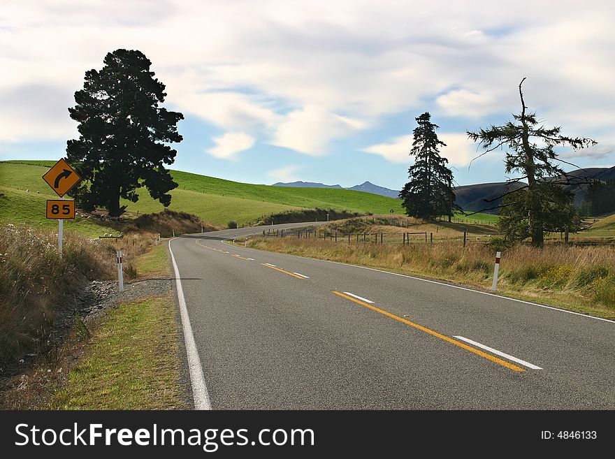 Winding road beside green rolling landscape. South Island. New Zealand