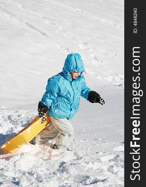 Boy going up to the snow hill with yellow plastic sled. Boy going up to the snow hill with yellow plastic sled