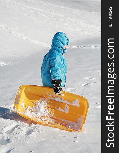 Boy going up to the snow hill with yellow plastic sled. Boy going up to the snow hill with yellow plastic sled