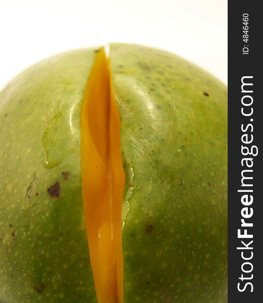 Close up image of a bright green mango with a small slice removed. Close up image of a bright green mango with a small slice removed.