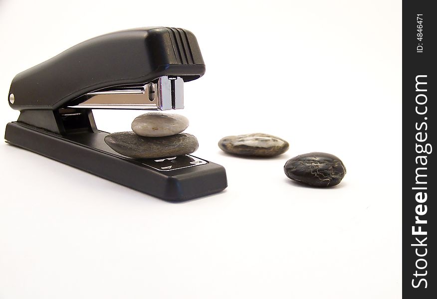 Image of a black stapler, about to staple two rocks together, with other rocks nearby.  Horizontal orientation. Image of a black stapler, about to staple two rocks together, with other rocks nearby.  Horizontal orientation.