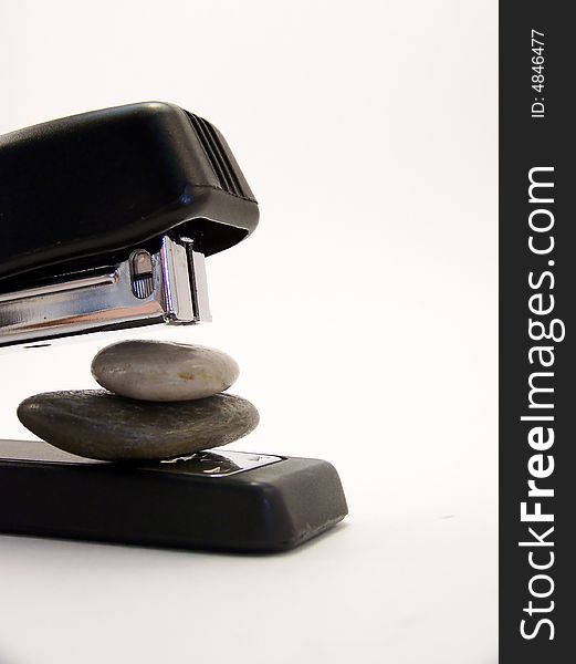 Close up image of a black stapler about to staple together two stones.  Vertical orientation. Close up image of a black stapler about to staple together two stones.  Vertical orientation.