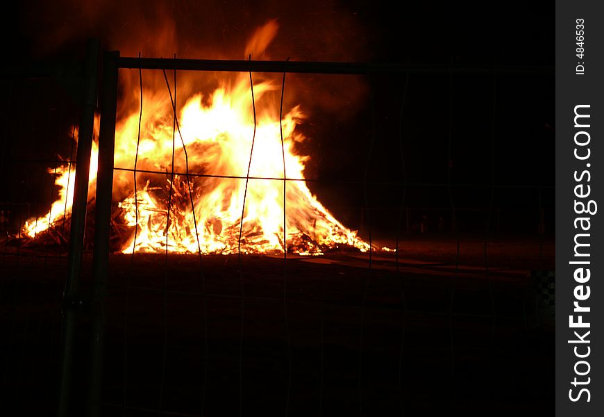 Big bonfire with huge flames behind bars. Big bonfire with huge flames behind bars