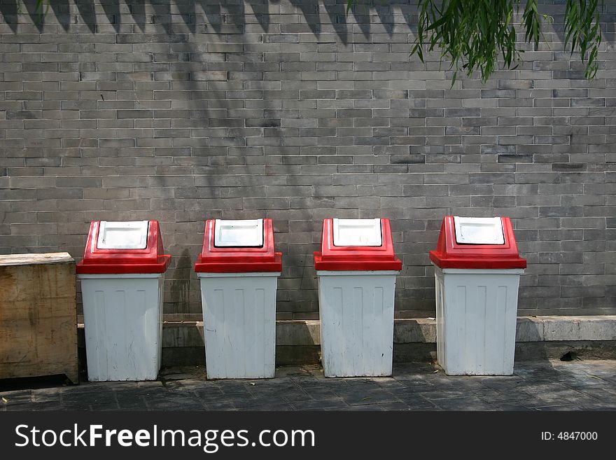 Four metallic trash bins beside the bricks wall