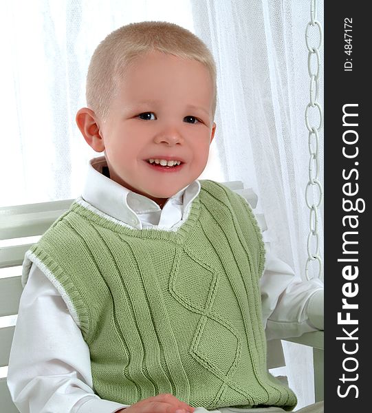 Young boy in green on swing and on white background. Young boy in green on swing and on white background