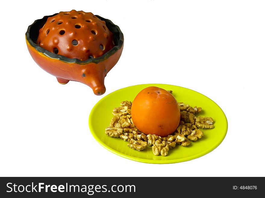 Circassian walnuts and persimmon on yellow plate and red ceramic hedgehog