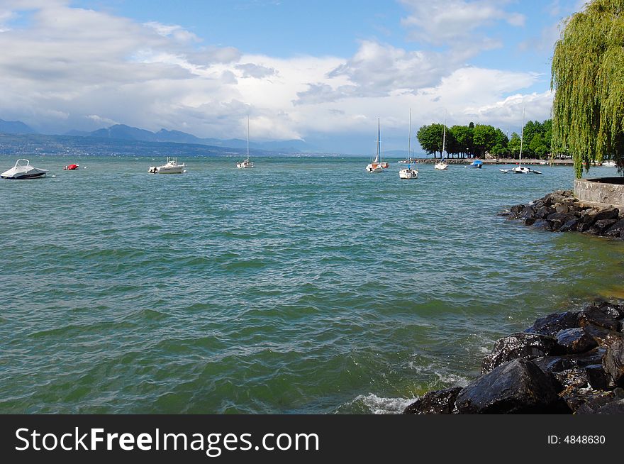 The landscape of lakeshore in Geneva lake, with clouds and blue sky. Lausanne, Switzerland. The landscape of lakeshore in Geneva lake, with clouds and blue sky. Lausanne, Switzerland