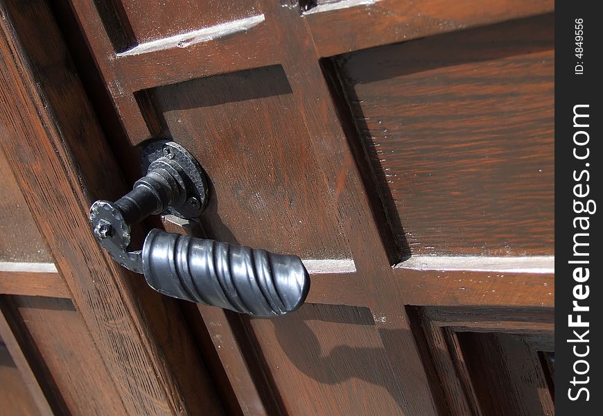 The wooden door with ornamental door handle. The wooden door with ornamental door handle.