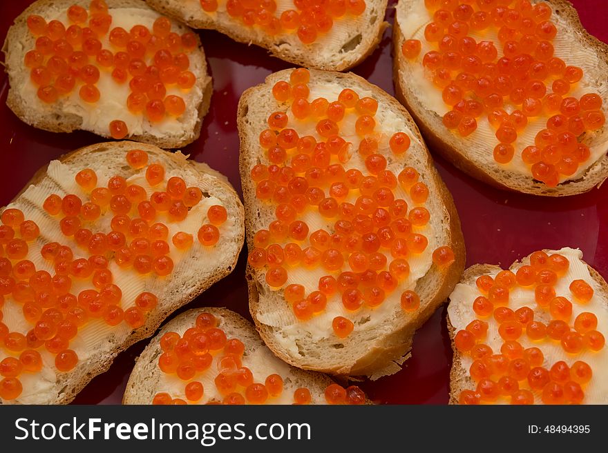 Bread and butter with red selmon caviar on a red plate. Bread and butter with red selmon caviar on a red plate.