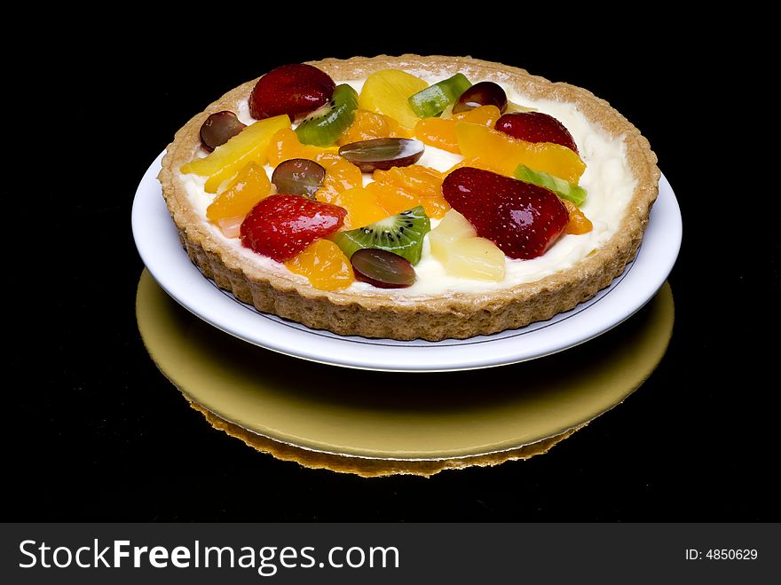 A fruit pie in a plastic transparent box on a gray to white background
