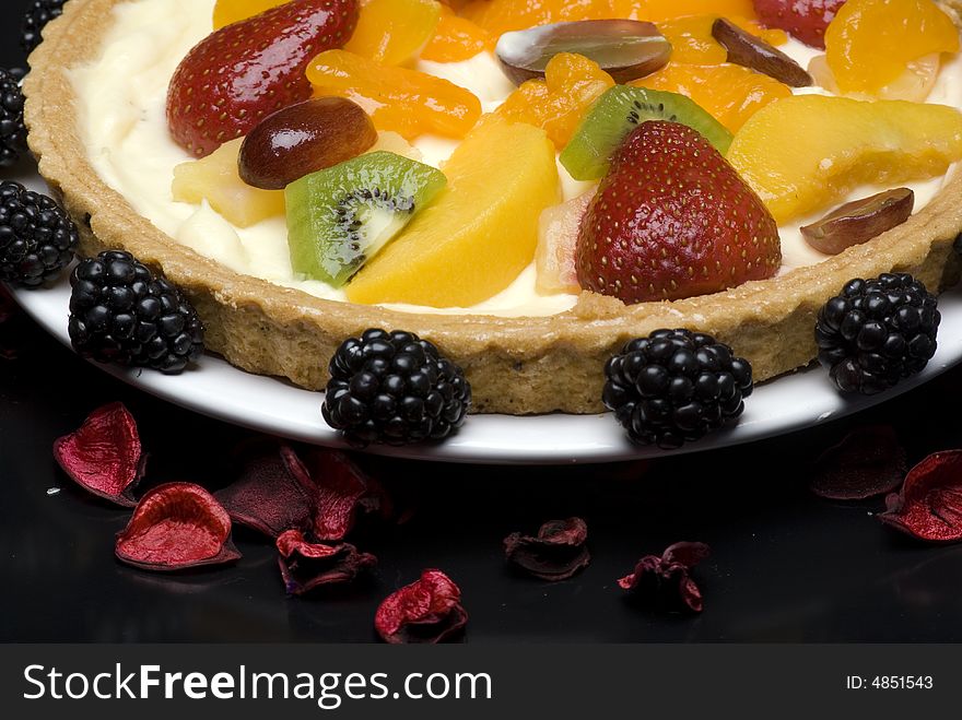 A fruit pie on a white plate on a black background