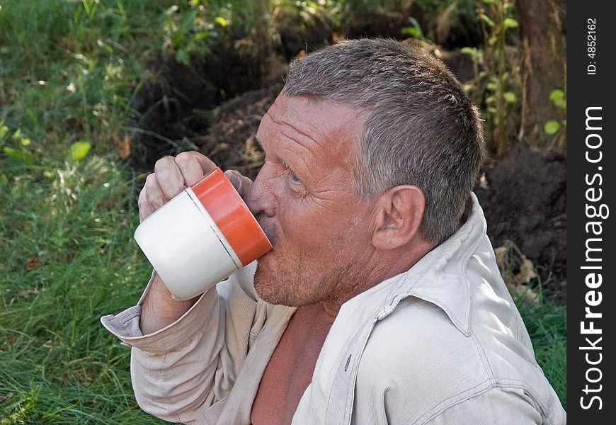 Portrait of thirsty man with a cup outdoors at hot summer day