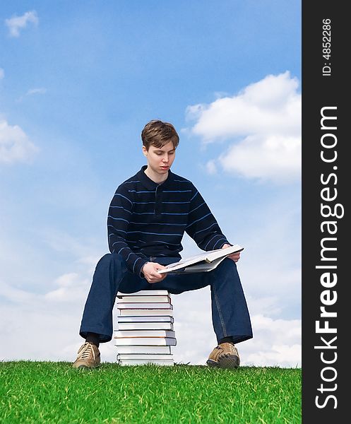 The young student with the books on a background of the blue sky