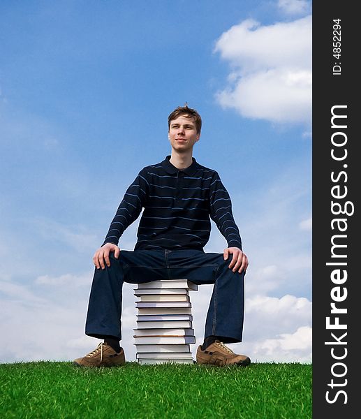 The young student with the books on a background of the blue sky