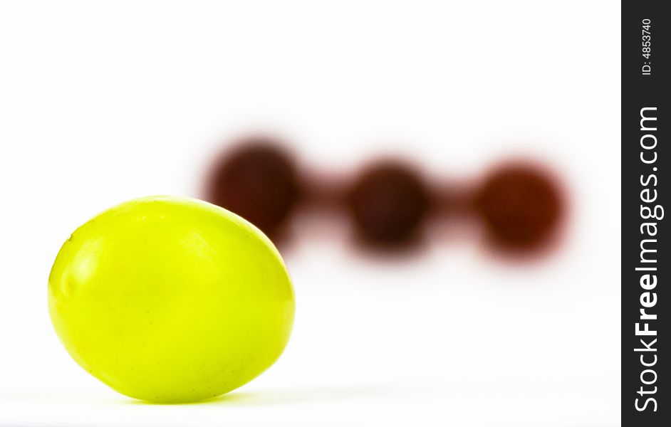 Green Grape in front of Three red grapes