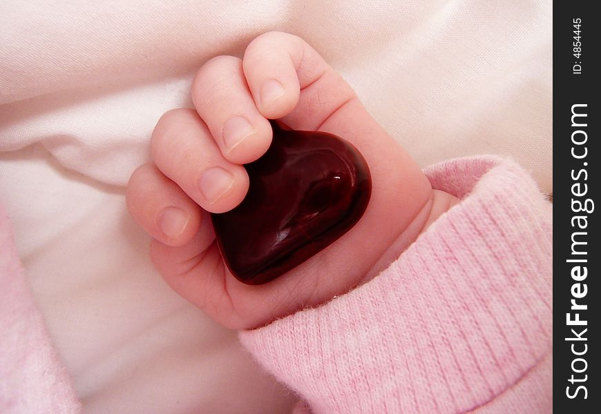 Little girl's hand with red glass heart