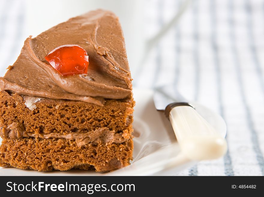 Slice of chocolate cake with a cherry on a plate